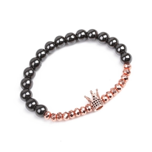 Detail of beaded hematite bracelet with rose gold zircon crown charm on white background