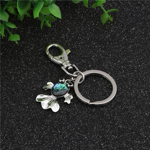Macro detail of silver fish-shaped keychain with rainbow abalone shell inlay on metal
