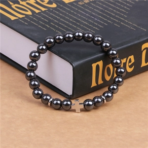 Black magnetic hematite 8mm beaded bracelet with silver cross pendant on a book