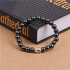Close-up of magnetic hematite bead bracelet with a golden Buddha head on a book