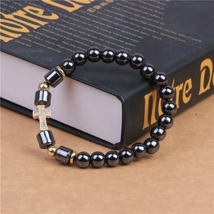Detail of 8mm hematite beaded bracelet with a gold rhinestone cross charm on a book