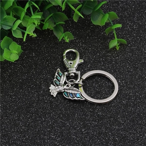Macro detail of bird keychain showing iridescent shell inlay and silver finish