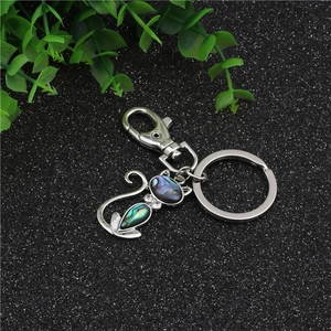 Macro detail of cat-shaped keychain with iridescent abalone shell inlay and lobster clasp