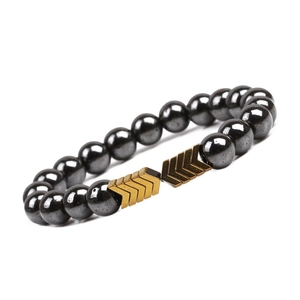 Detailed macro view of magnetic hematite beads with golden V-shaped arrow metal accents