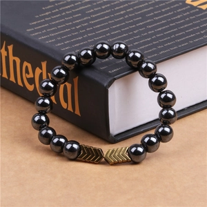 Macro shot of magnetic hematite beaded bracelet with golden V-shaped arrow metallic accents