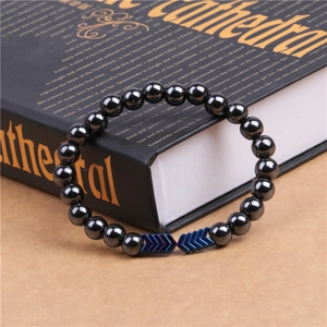 Close-up of magnetic hematite beaded bracelet with blue-purple chevron accents by a book