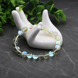 Détail d'un bracelet en perles de pierre de lune avec effet aurora sur un support main