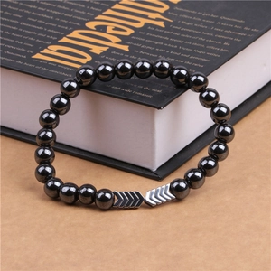 Macro detail of men's magnetic hematite beaded bracelet with silver arrow charms