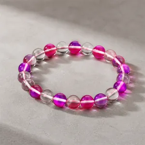 Vue détaillée d'un bracelet en perles de verre dégradé rose et violet sur un modèle de main