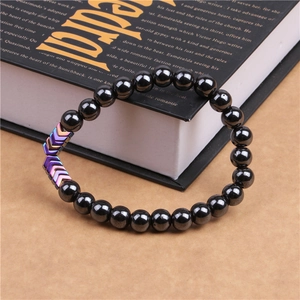 Macro shot of magnetic hematite bracelet with rainbow arrow beads on a black book
