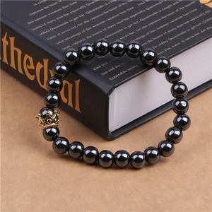 Detailed close-up of a black hematite bead bracelet with a gold zircon crown charm