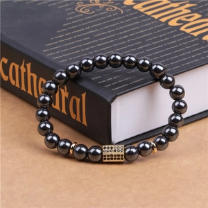 Macro detail of men's magnetic hematite beaded bracelet with gold pave crystal bar charm