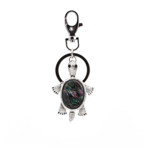 Macro detail of silver sea turtle keychain featuring colorful iridescent abalone shell inlay