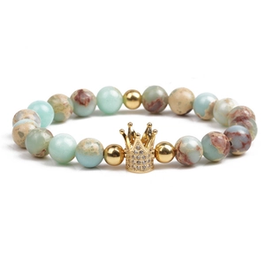 Macro detail of natural stone beaded bracelet with gold crown charm and zircon inlay