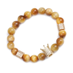 Bracelet en œil de tigre jaune avec breloque couronne dorée et zircons sur fond blanc