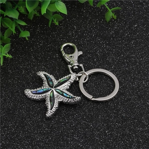 Macro detail of starfish keychain featuring iridescent blue-green abalone shell inlays
