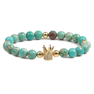 Imperial stone bead bracelet with a gold crown charm and zircon accents on white background
