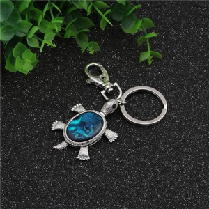 Detail of a turtle keychain with iridescent blue shell inlay and silver lobster clasp