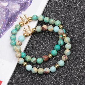 Macro detail of imperial stone beads with golden crown charms on elastic bracelets