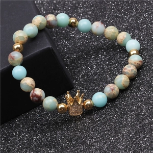 Macro detail of natural stone beads and gold crown charm with micro-inlaid zircons