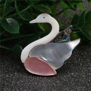 Broche cygne en nacre rose et aile en abalone sur fond sombre avec détails brillants