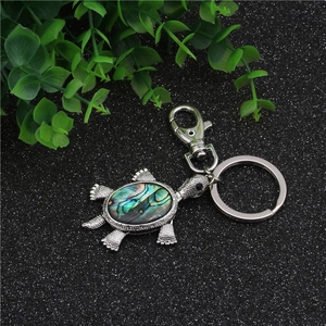 Detailed macro view of turtle keychain with iridescent abalone shell in silver metal