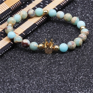 Macro detail of natural stone beads and gold crown charm with micro-inlaid zircons