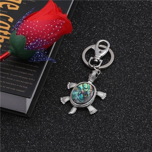 Detailed close-up of a silver turtle keychain with iridescent abalone shell inlay