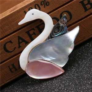 Broche cygne rose en nacre et nacre d'abalone présentée sur un fond de bois rustique