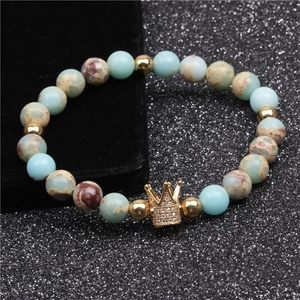 Macro view of blue zebra jasper beads and gold-toned crown charm on a beaded bracelet