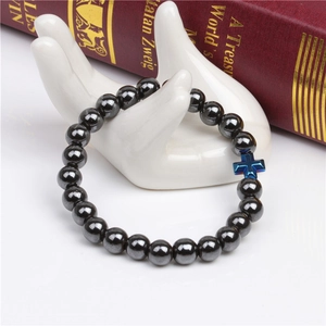 Detail of 8mm magnetic hematite bead bracelet with blue metallic cross charm