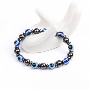 Detail of magnetic hematite beads and blue evil eye charms on white hand display