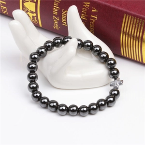 Detail of 8mm magnetic hematite bead bracelet with silver cross on white hand model