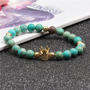 Macro shot of turquoise beads bracelet with a gold crown charm and micro-inlaid zircons