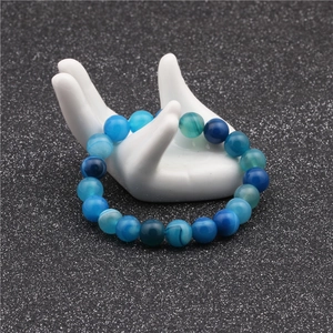 Detailed view of 10mm blue striped agate beads with natural textures on a white stand