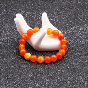 Close-up of 10mm polished orange agate beads on a classic beaded stretch bracelet