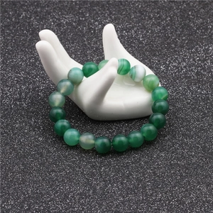 Detailed close-up of 10mm green agate beads with natural striped texture on display