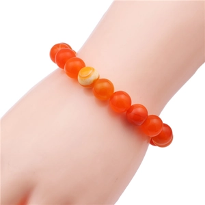 Detail of red agate beaded bracelet on wrist featuring a natural striped silk eye bead