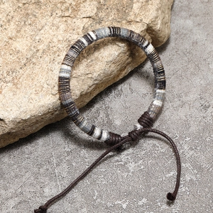 Detailed close-up of bohemian woven friendship bracelet on a natural stone surface