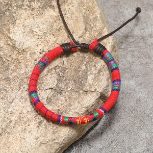 Detail of red woven bohemian friendship bracelet with ethnic patterns and adjustable cord