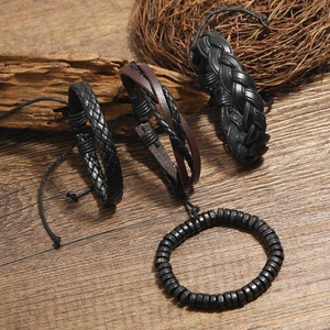 Set of 4 vintage men's leather bracelets with woven straps and wood beads on wood background