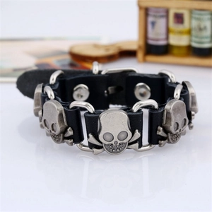 Detail of a punk black leather bracelet featuring silver metal skull studs and buckle