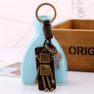 Retro bronze robot keychain with woven leather strap and metal charm on blue vase