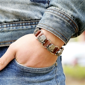 Punk style brown genuine leather bracelet with bronze skull charms on denim backdrop