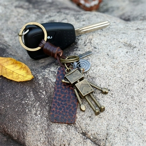 Macro view of vintage bronze robot charm with woven leather keychain on stone background