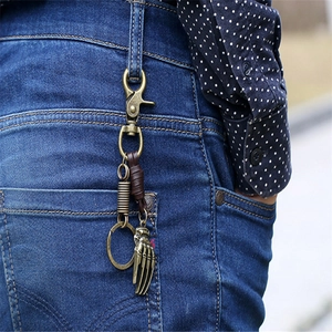 Vintage bronze skeleton hand keychain with leather strap on blue jeans denim
