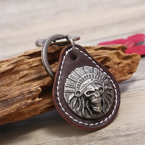 Vintage punk leather keychain with carved silver skull on rustic wooden background