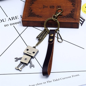 Porte-clés robot industriel vintage en alliage de bronze et cuir sur une boîte rustique