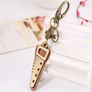 Retro punk bronze saw keychain with leather detail hanging on a white wooden chair