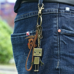 Porte-clés robot vintage en bronze avec lanière en cuir sur un jean bleu